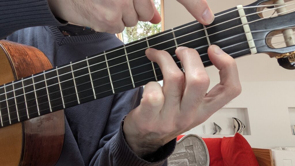 Fingering of the F major chord on the guitar using two hands.